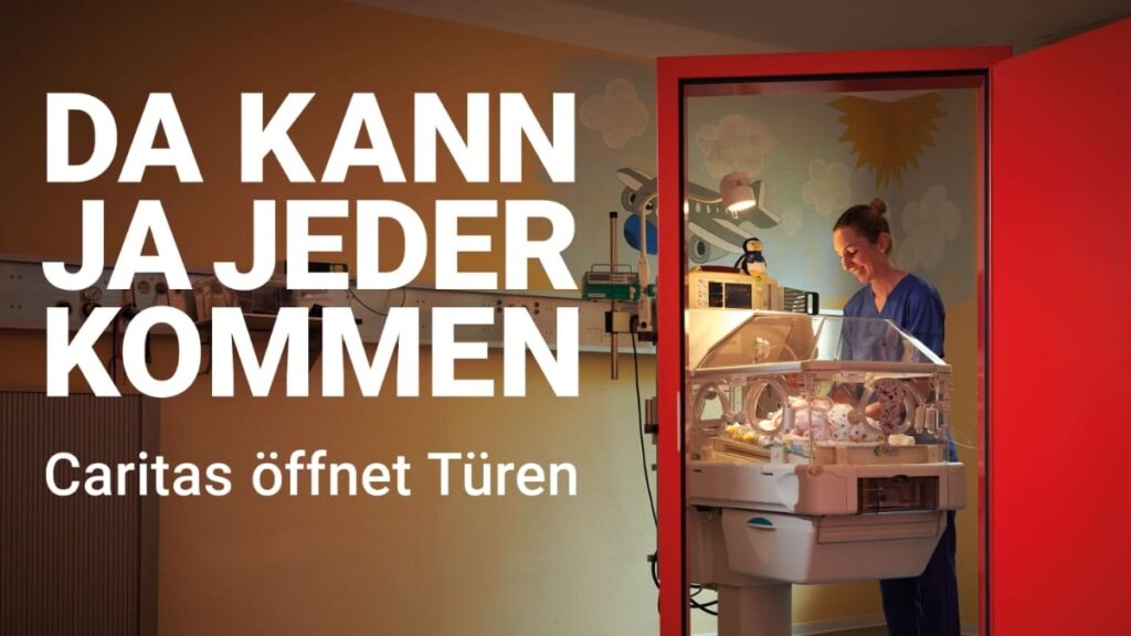 Bild zeigt den Blick in einen Raum. Rechts eine geöffnete rote Tür. Im Raum ein Brutkasten mit einem Neugeborenen Baby und einer lächelnden Pflegeperson. Text: Da kann ja jeder kommen. Caritas öffnet Türen.