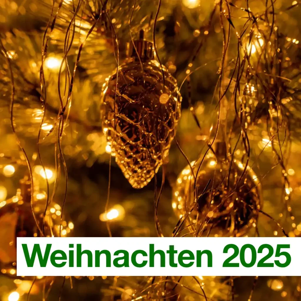 Das Bild zeigt einige Zweige eines Weihnachtsbaumes, die in gelbliches Licht getaucht sind. Im Baum hängen goldene Weihnachtskugeln in klassischer Form und in Form von Tannenzapfen. Text: "Weihnachten 2025".