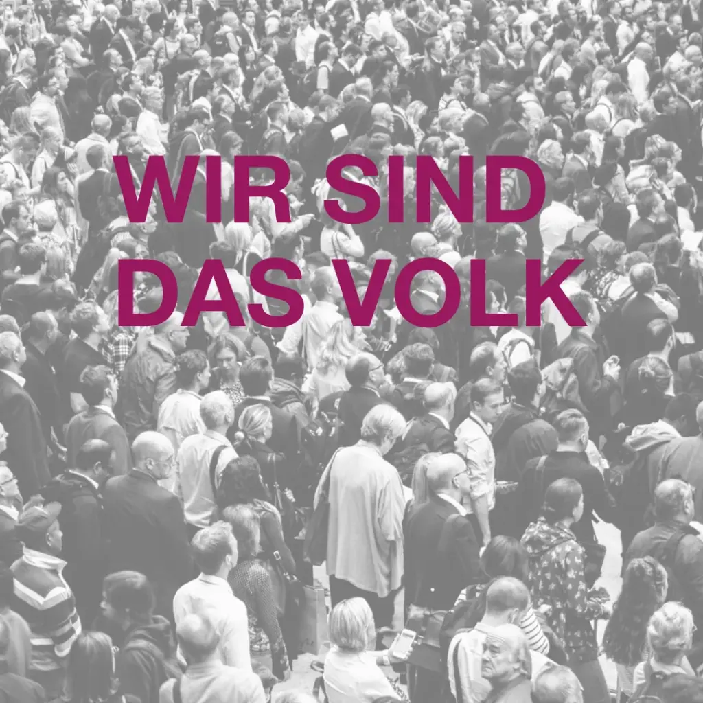 Das Bild zeigt eine große Menschenmenge von oben fotografiert. Text: Wir sind das Volk.